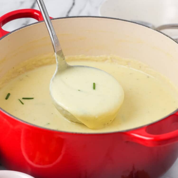 a red dutch oven filled with homemade creamy potato leek soup.