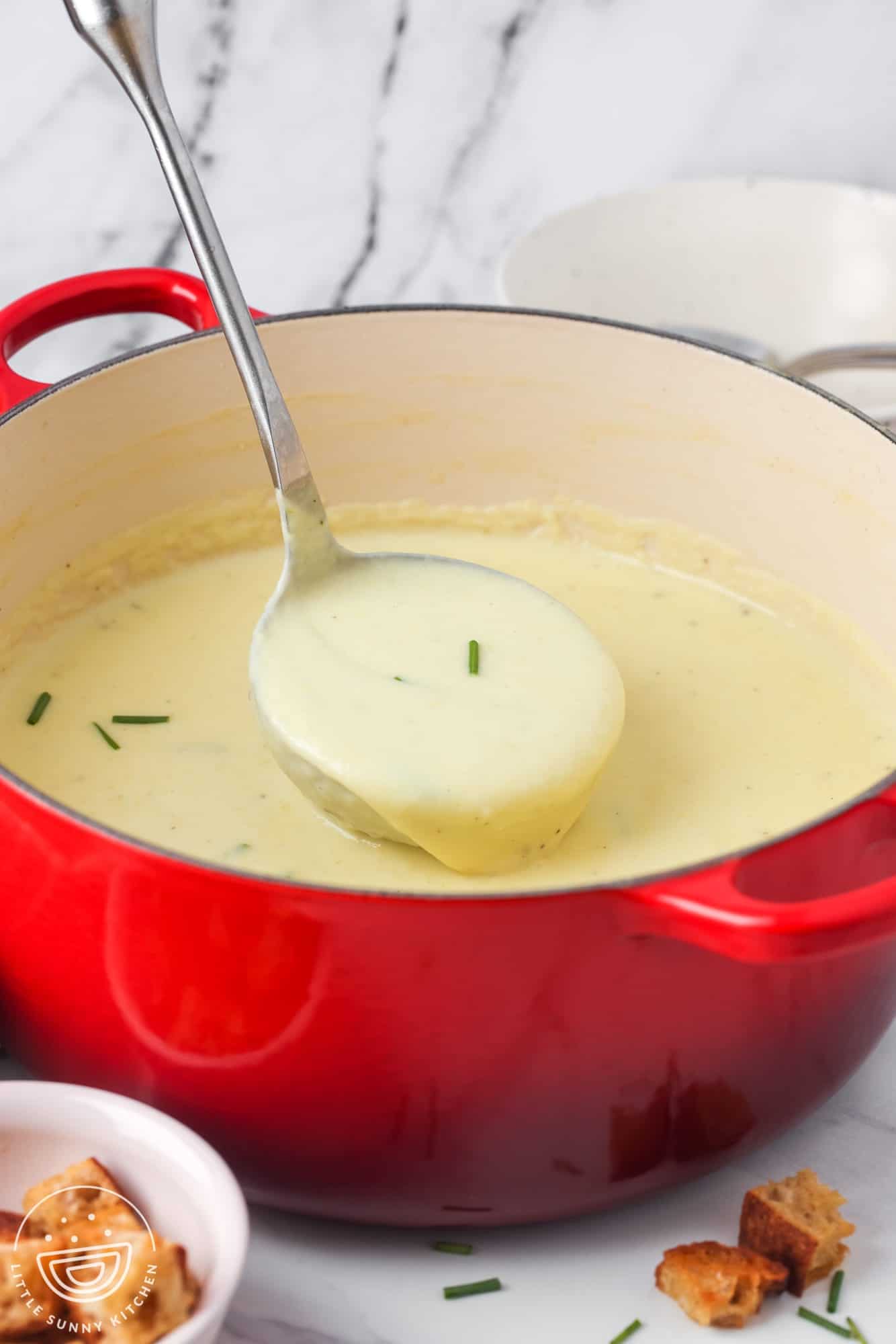 a red dutch oven filled with homemade creamy potato leek soup.