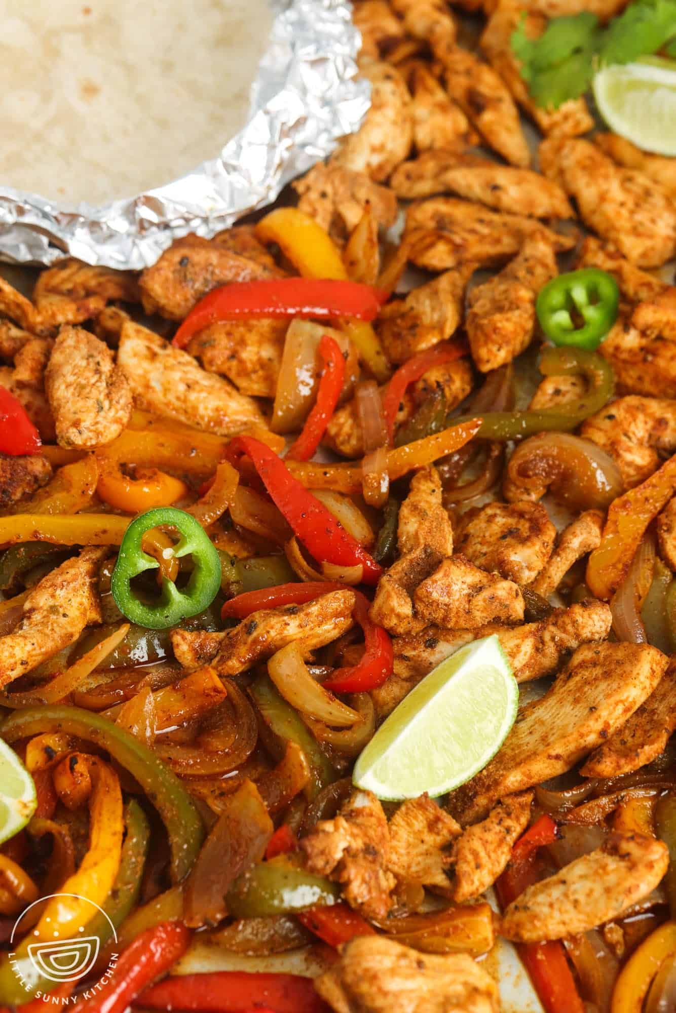 Chicken, peppers, and onions, cooked, on foil.
