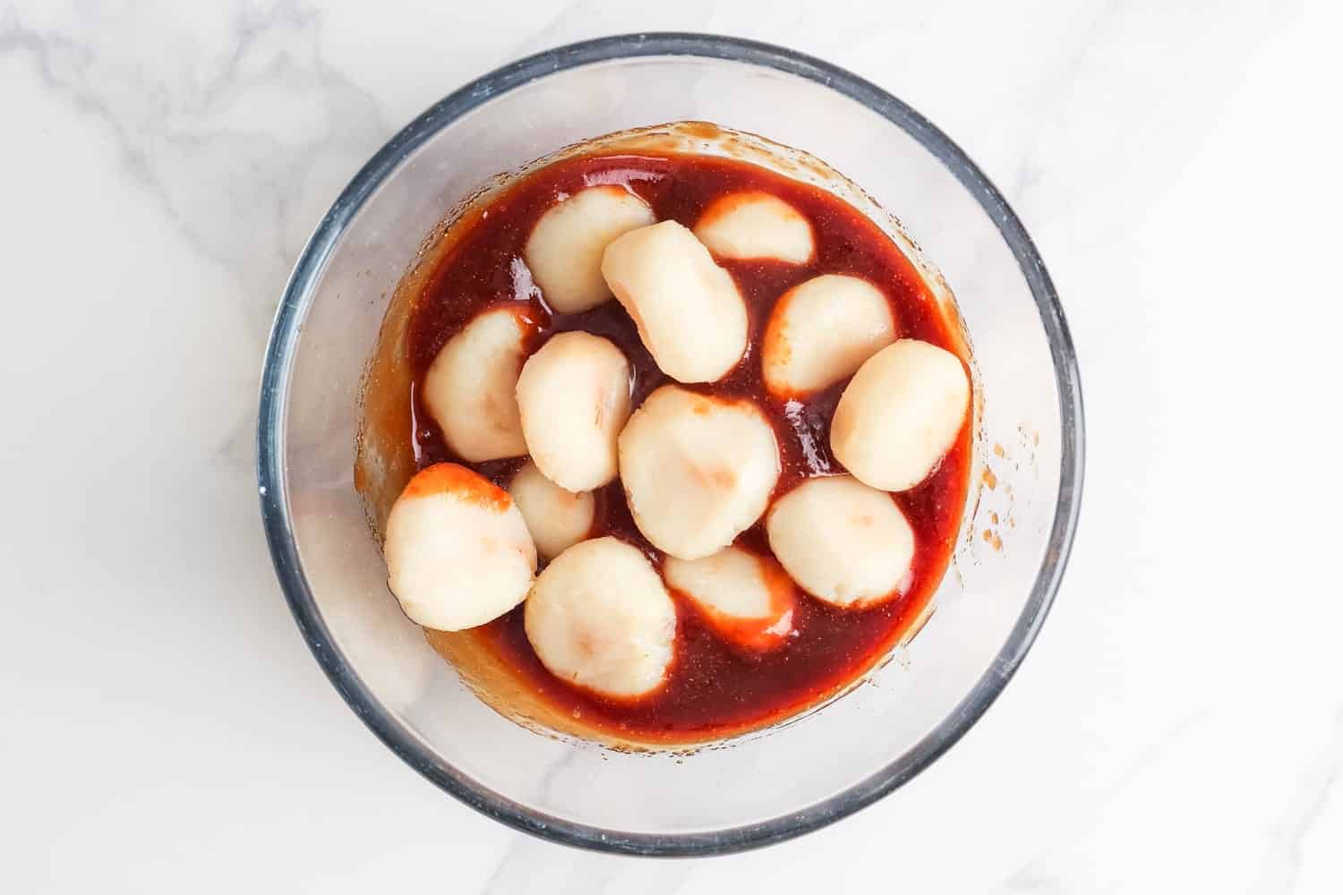 whole water chestnuts in a bowl with a ketchup soy sauce glaze. 