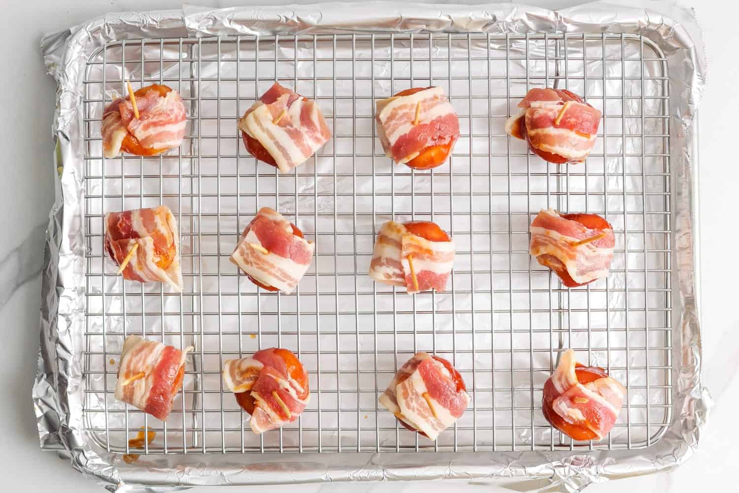 12 bacon wrapped water chestnuts on a wire rack over a foil lined sheet pan. 