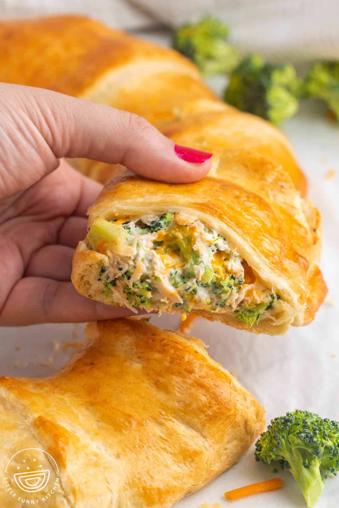 Taking a cheesy chicken and broccoli crescent slice off a larger ring