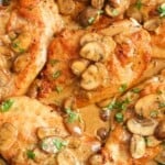 chicken cutlets in marsala wine sauce with mushrooms, in a stainless steel skillet.