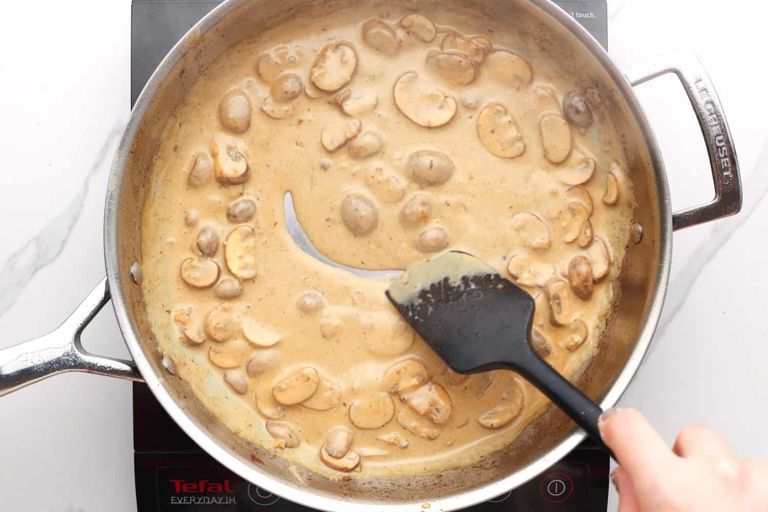 a creamy marsala wine sauce with mushrooms in a metal skillet. 