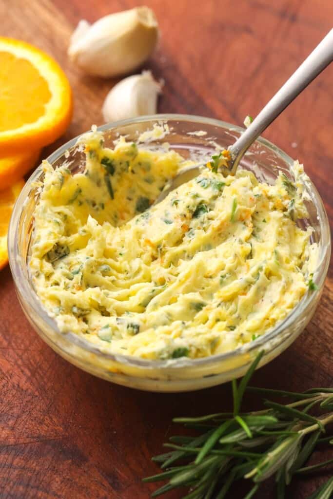 A bowl of herb butter for christmas chicken that includes minced garlic, parsley, rosemary, orange zest.