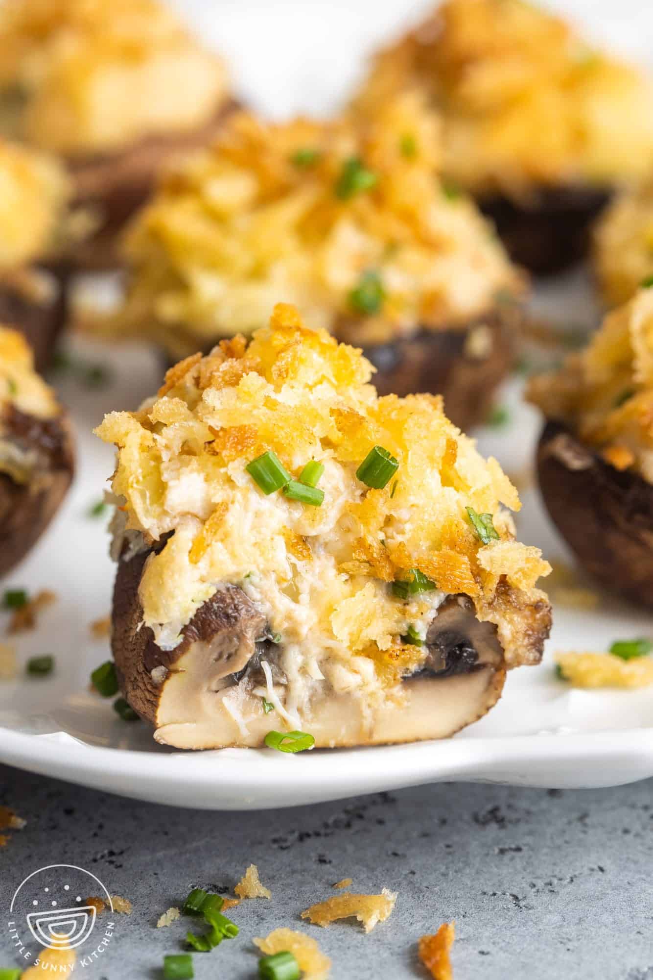 closeup of a crab stuffed mushroom that has been cut in half to show what it looks like inside, gooey and cheesy.