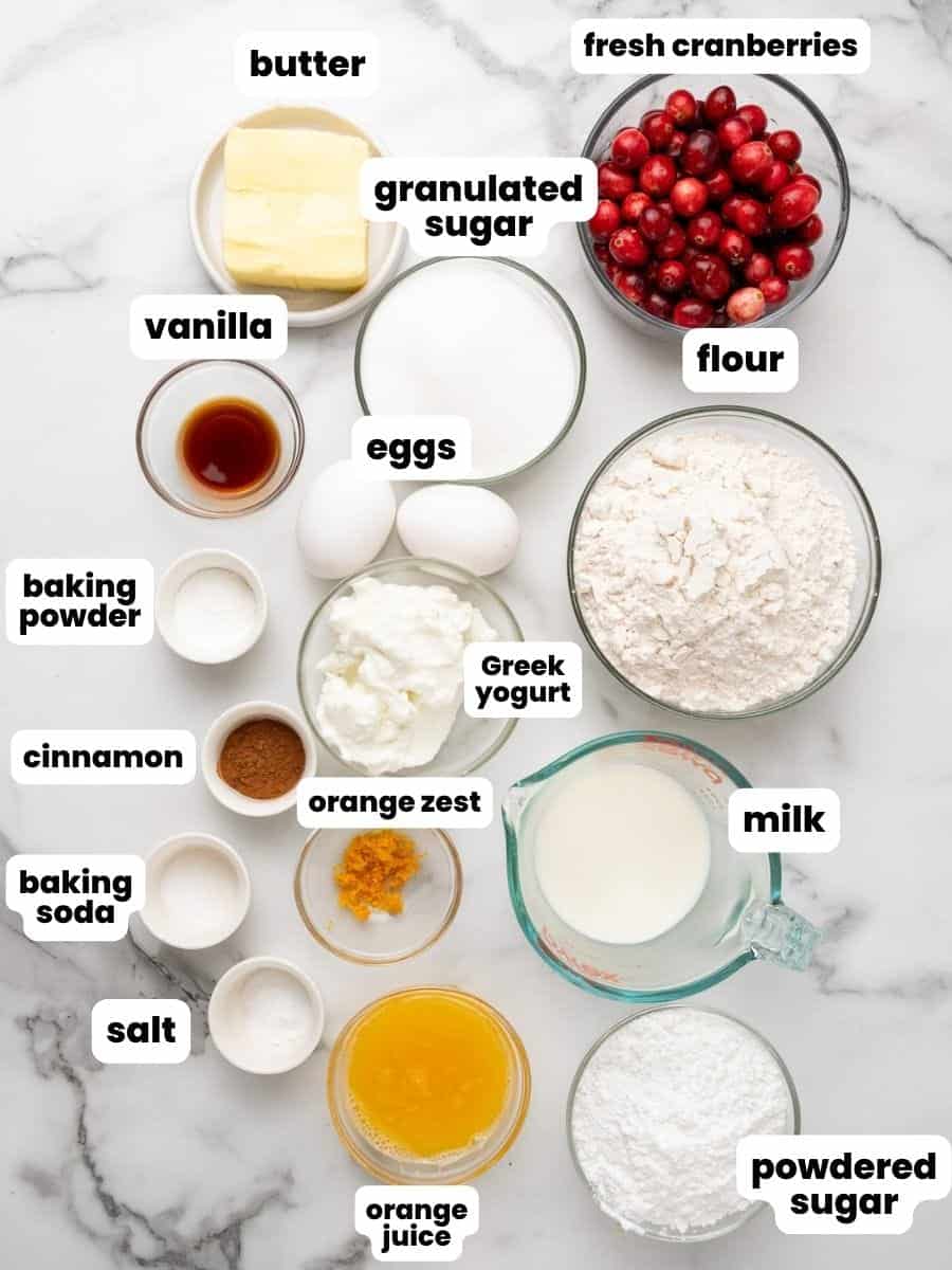 Small bowls arranged on a marble counter, holding the ingredients needed to make cranberry orange muffins. 