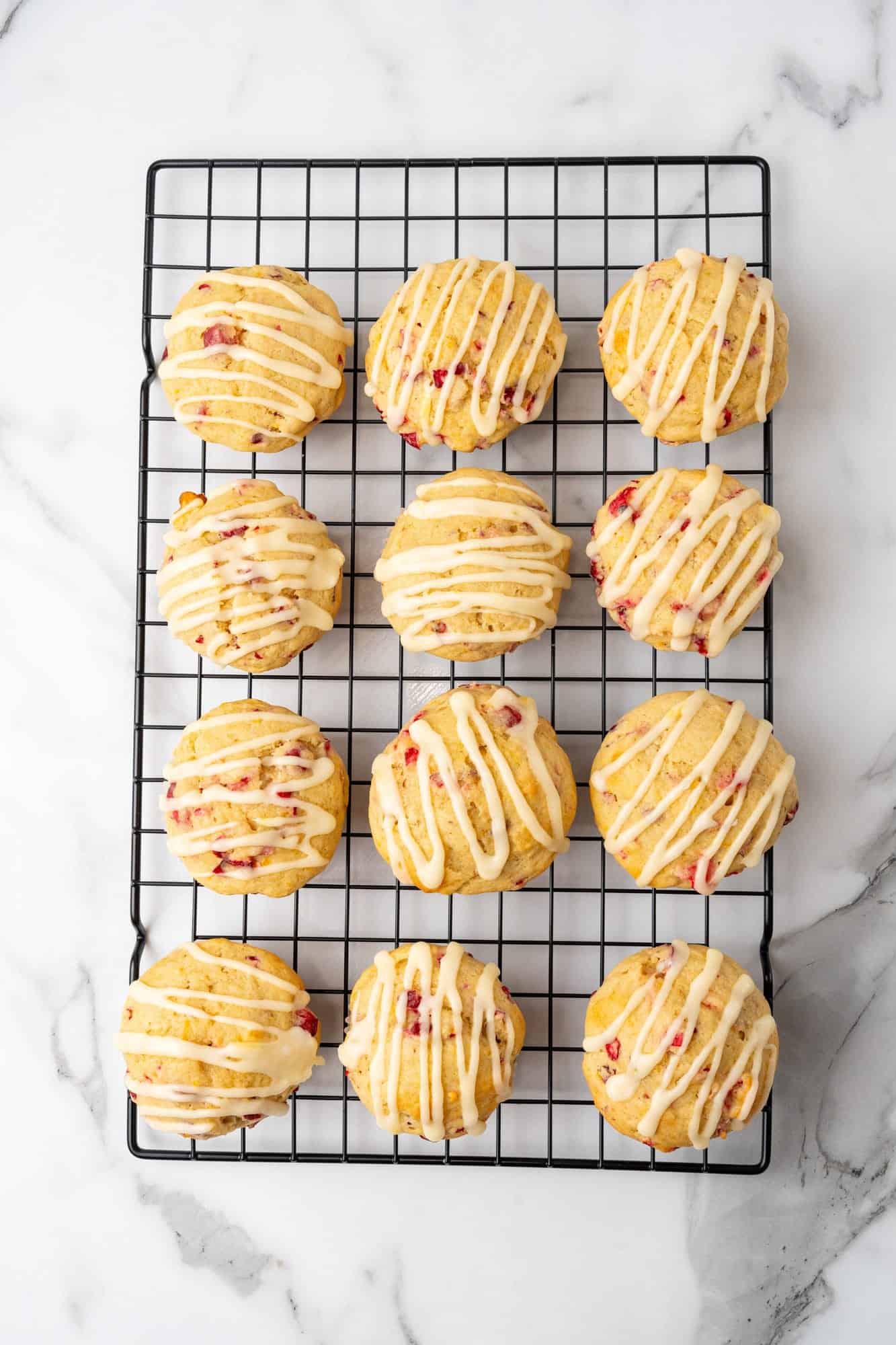 cranberry orange muffins on a cooling rack, drizzled with icing. 