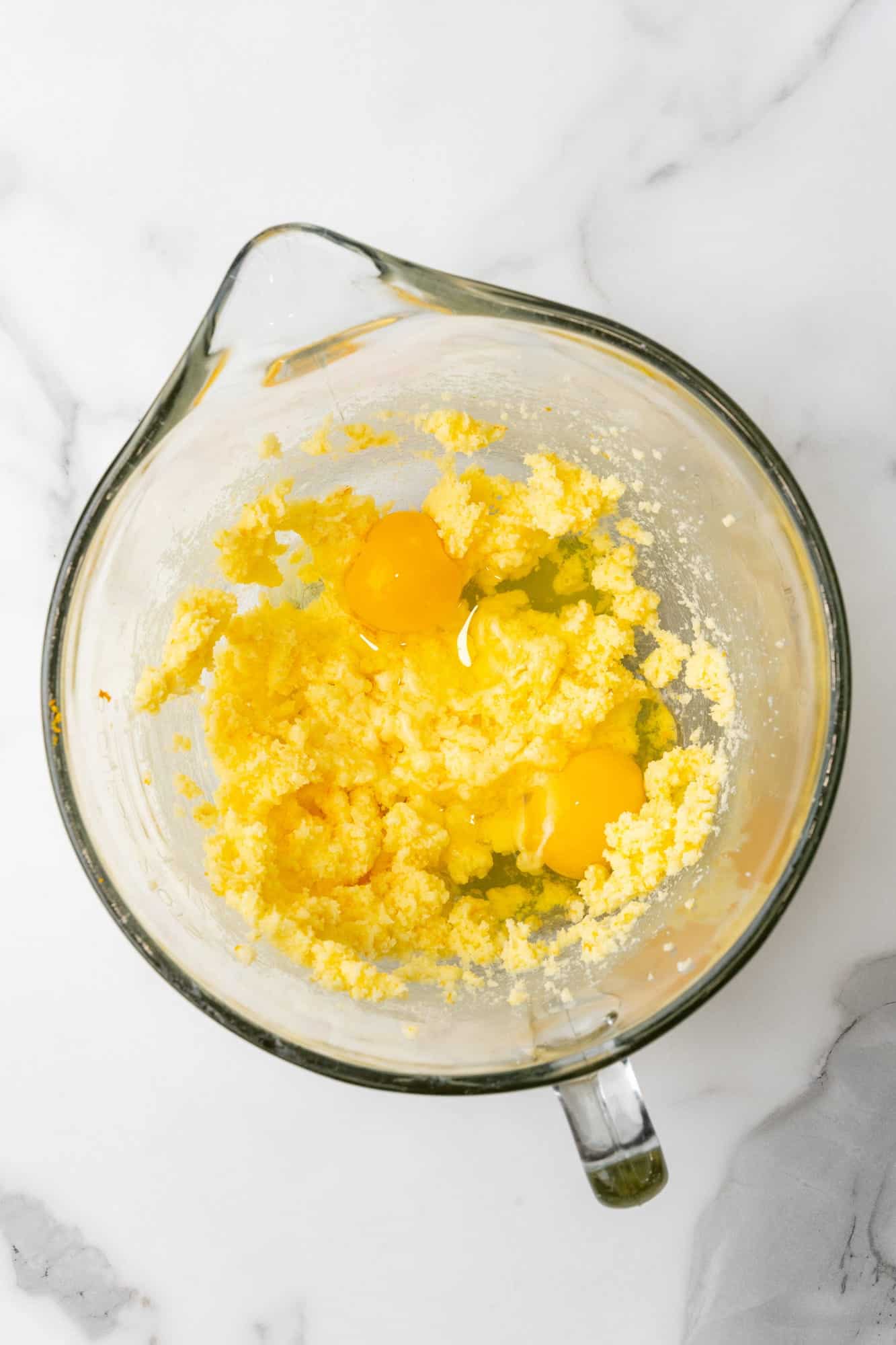 eggs added to creamed butter and sugar in a glass mixing bowl. 