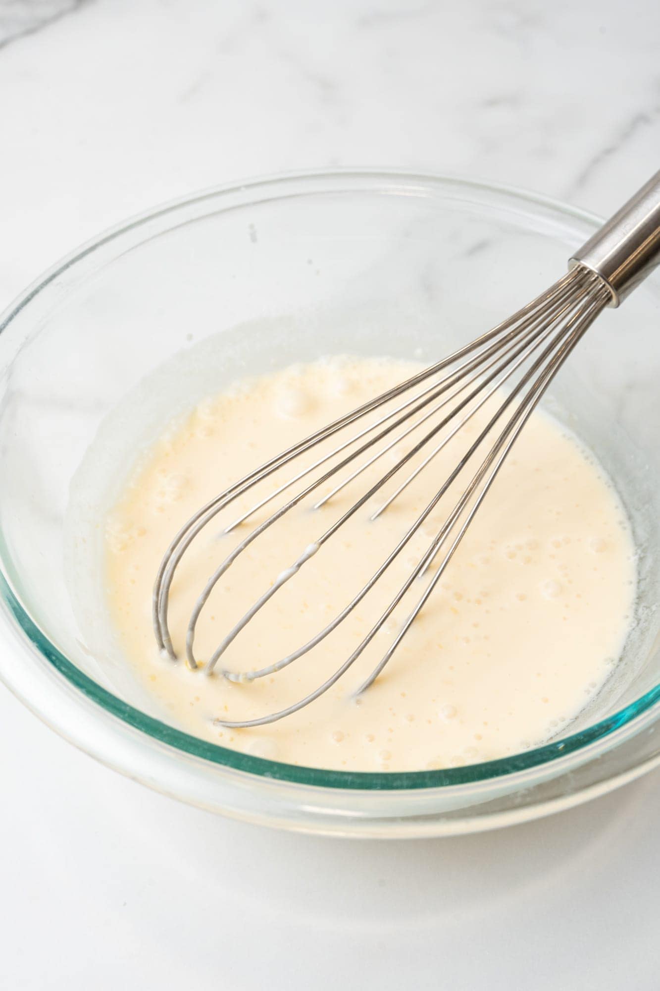 milk in a glass bowl with a whisk. 