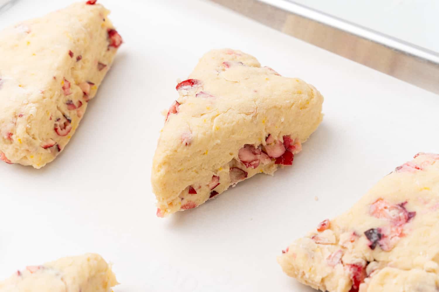 unbaked cranberry orange scones on a parchment lined baking sheet. 