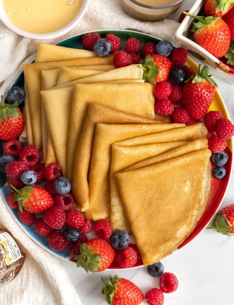 a plate holding folded crepes and fresh berries.