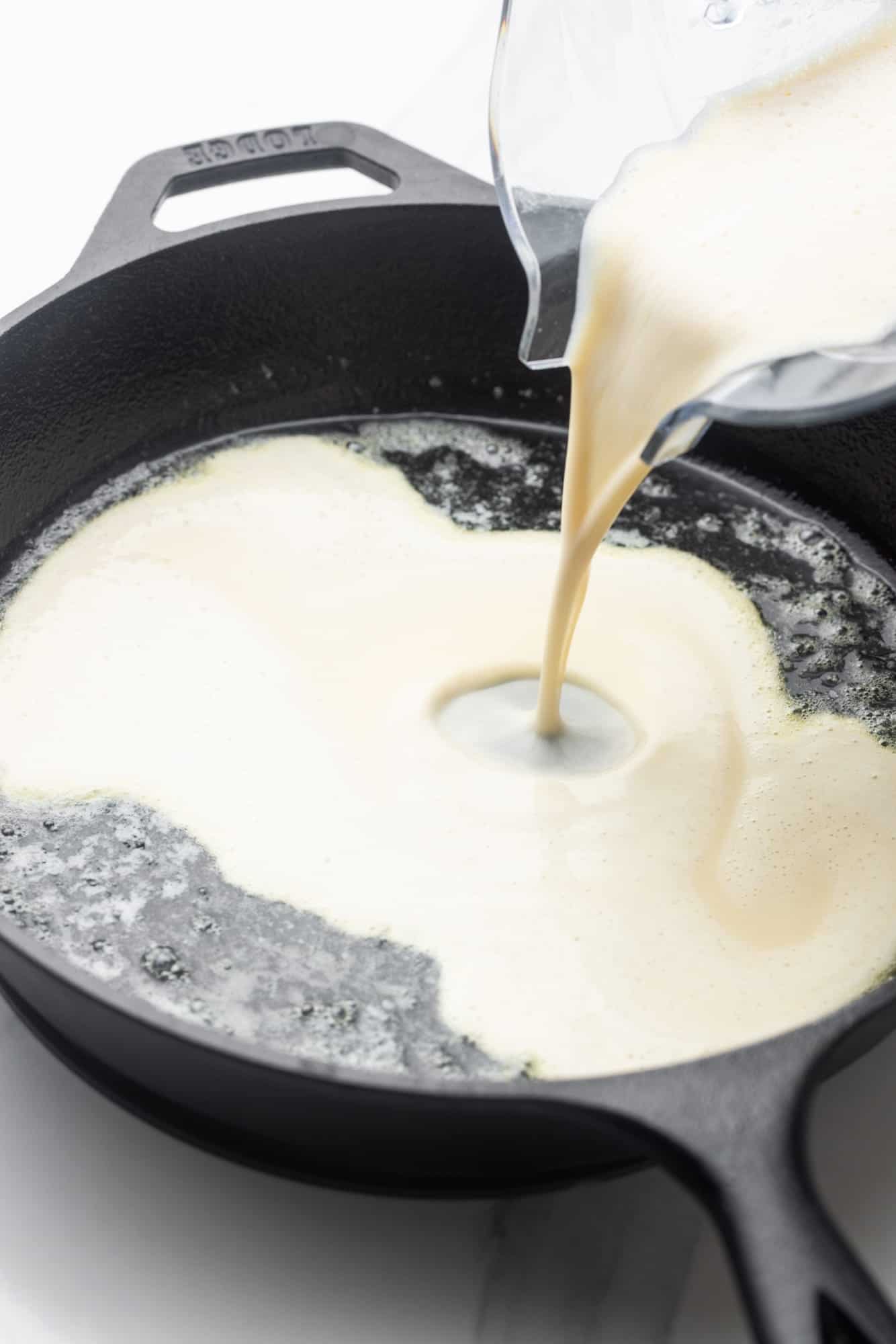Dutch baby pancake batter poured into a buttered cast iron skillet.