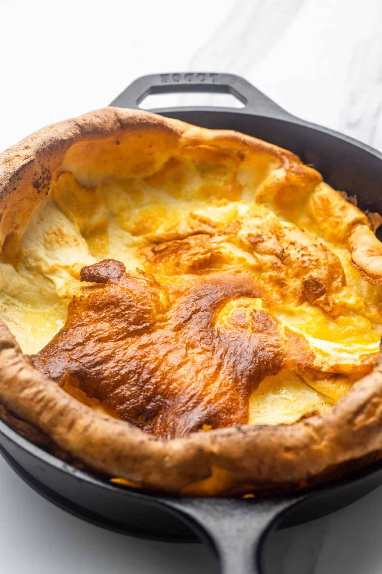 a puffy, fluffy, dutch baby pancake in a lodge cast iron skillet.