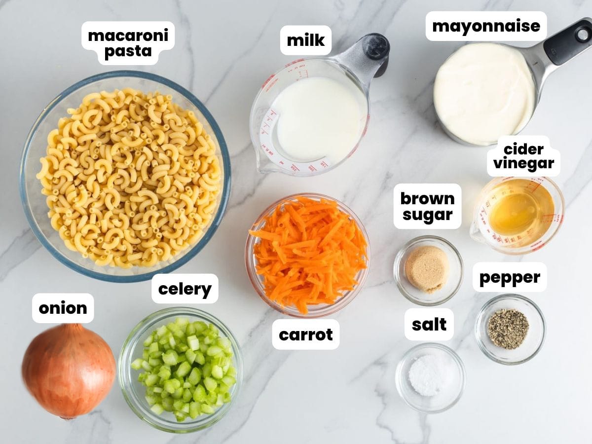The ingredients for hawaiian macaroni salad, all in separate bowls, arranged on a marble counter.