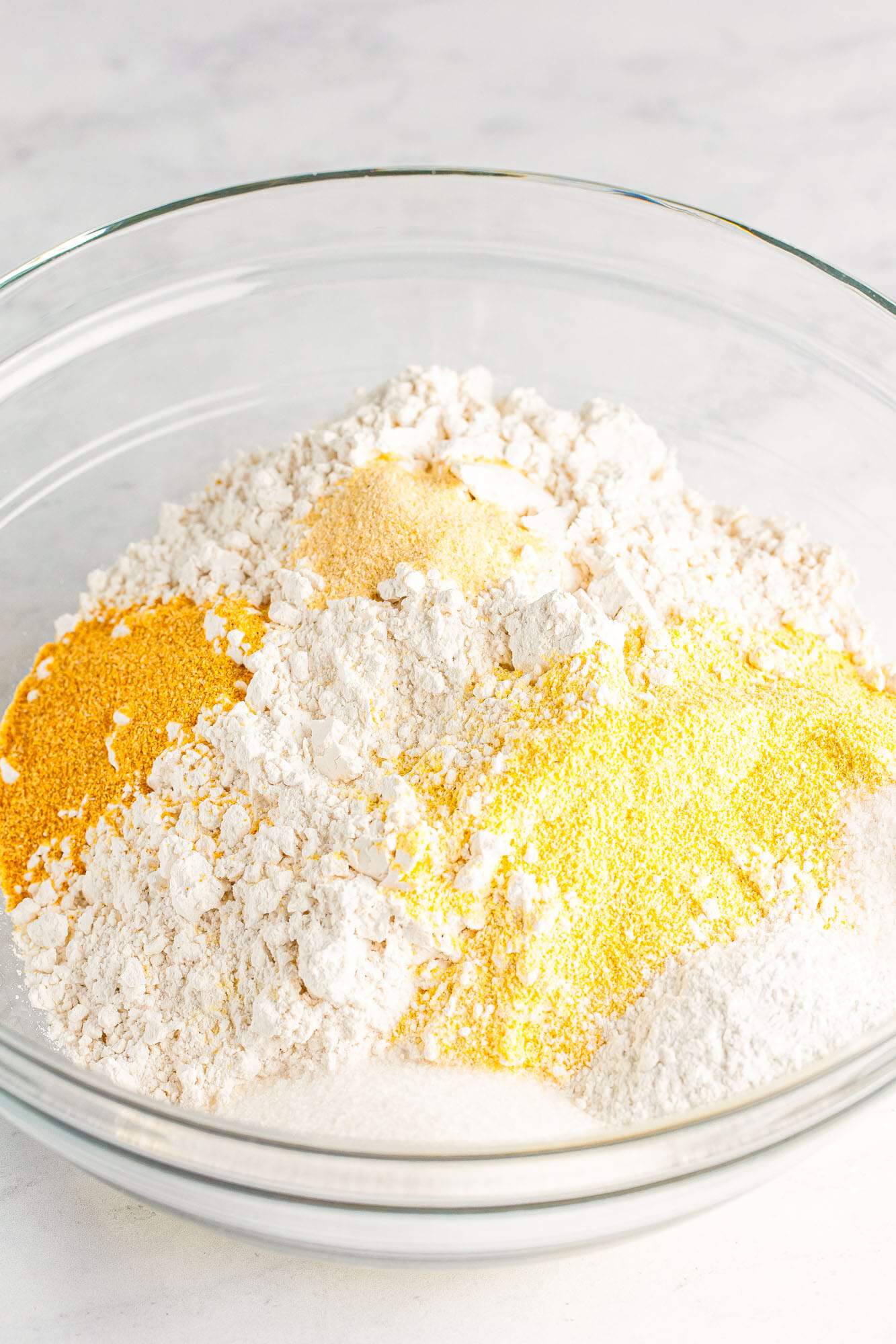flour, cornmeal, and seasonings in a glass bowl for corn dog batter. 