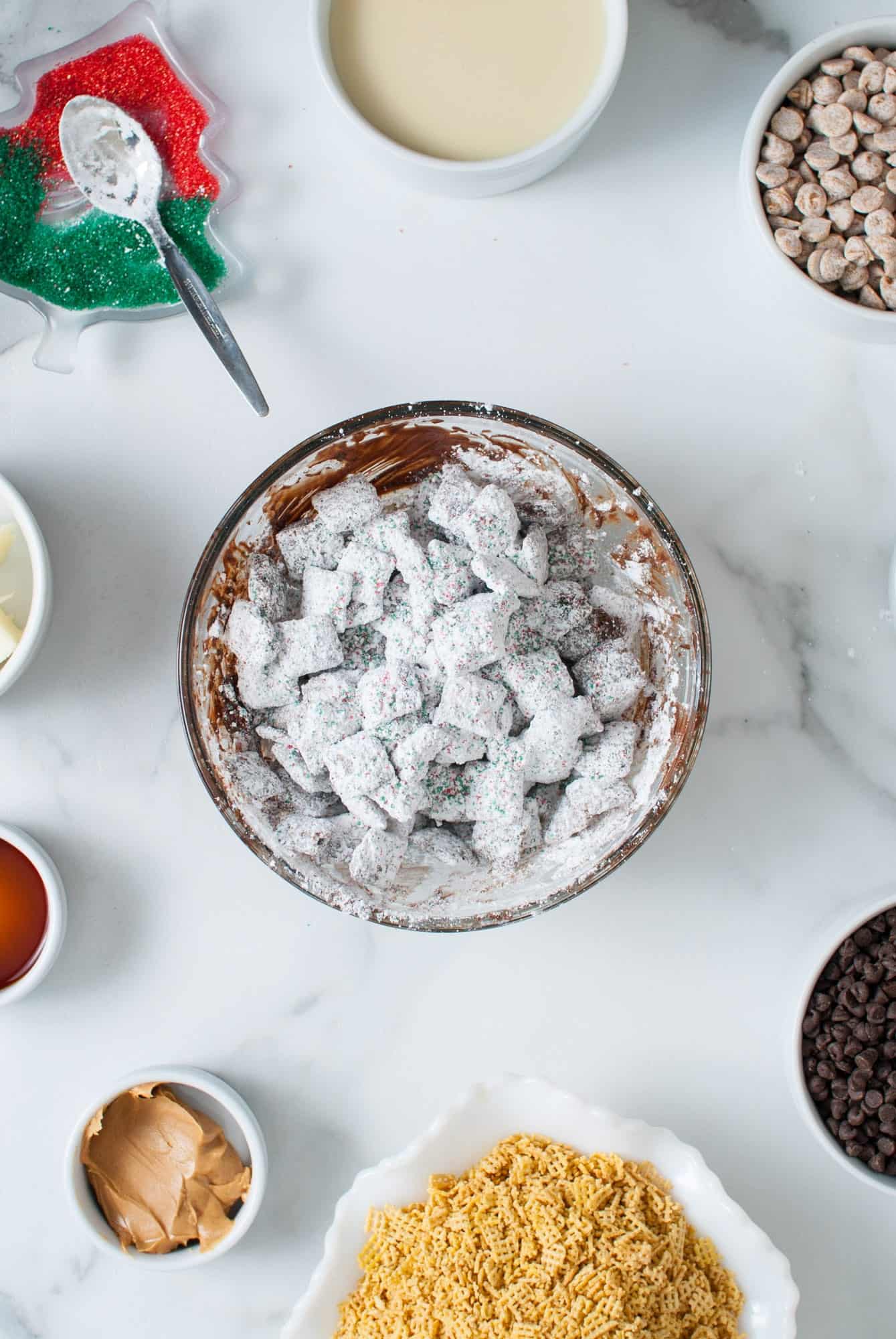 a glass mixing bowl of powdered sugar coated puppy chow. 