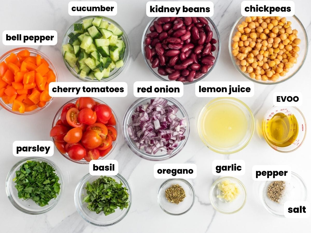 several small clear bowls arranged on a counter. Each holds a single ingredient needed to make red kidney bean salad. Some are filled with beans, others diced vegetables, others seasonings and dressing.