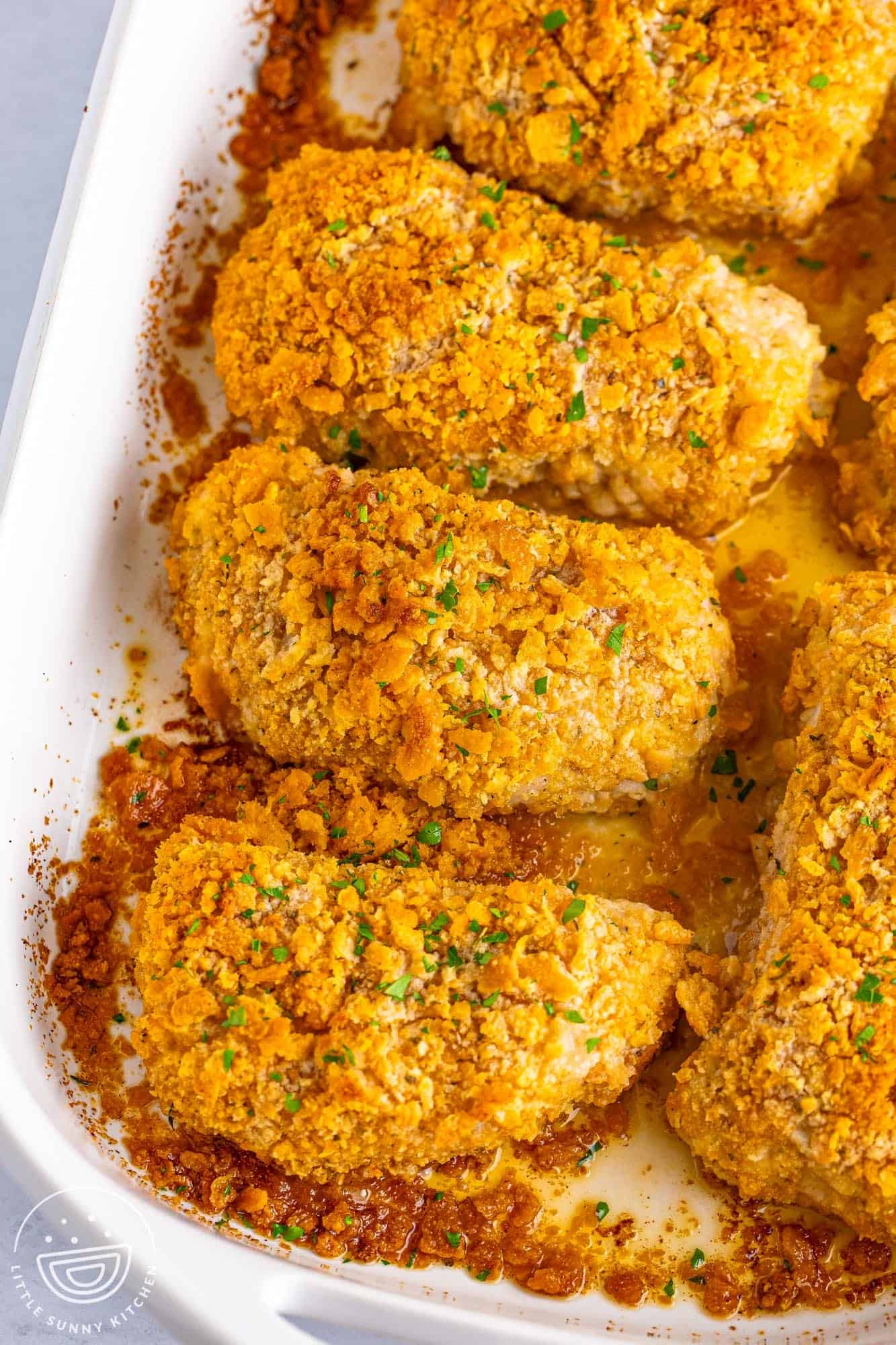 a casserole dish filled with crispy baked pork chops with a ritz cracker coating. 