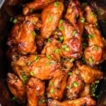bbq chicken wings in a black slow cooker, viewed from above.