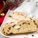 sliced stollen on a square plate showing the ribbon of marzipan in the center as well as raisins and candied peel.
