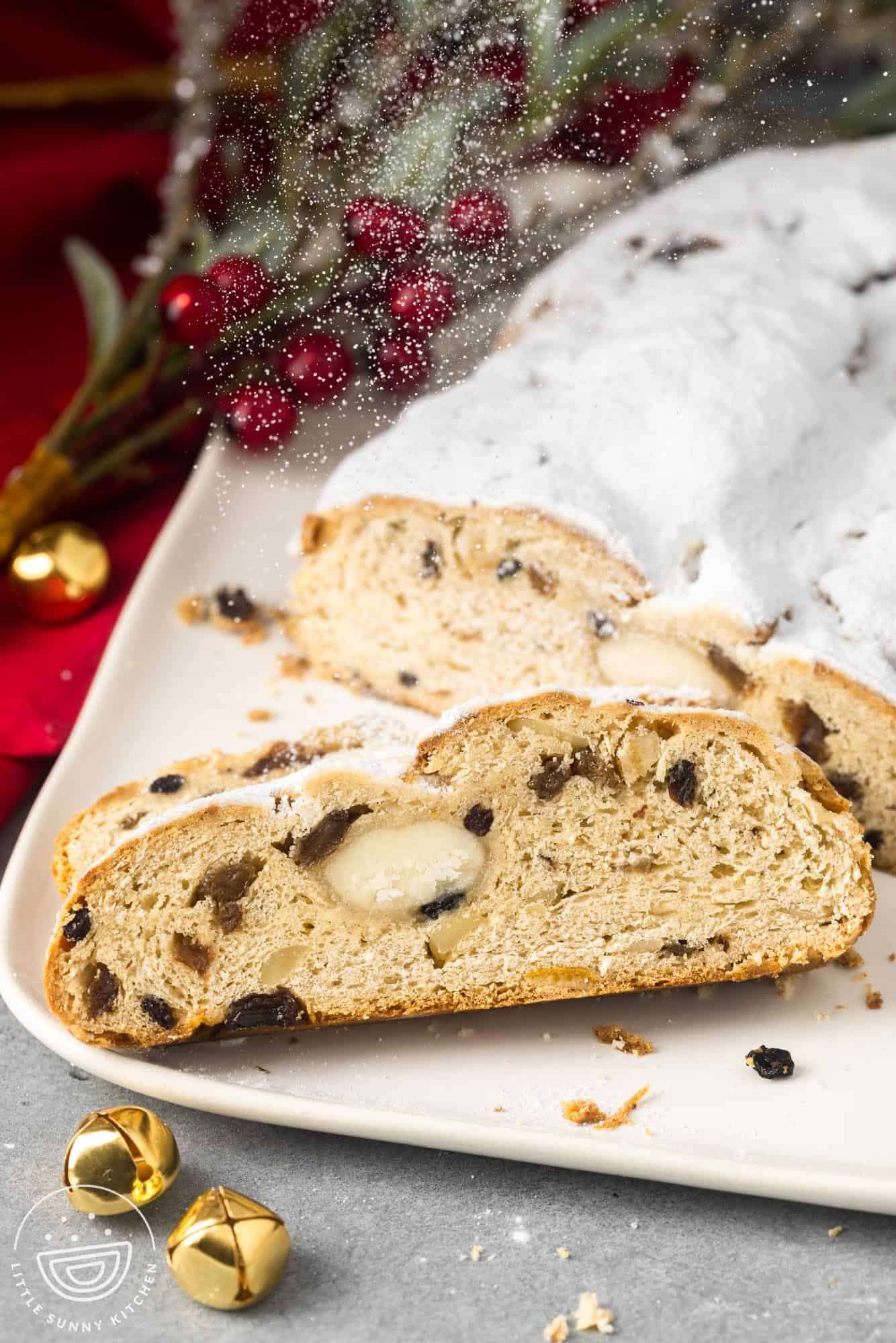 sliced stollen on a square plate showing the ribbon of marzipan in the center as well as raisins and candied peel.