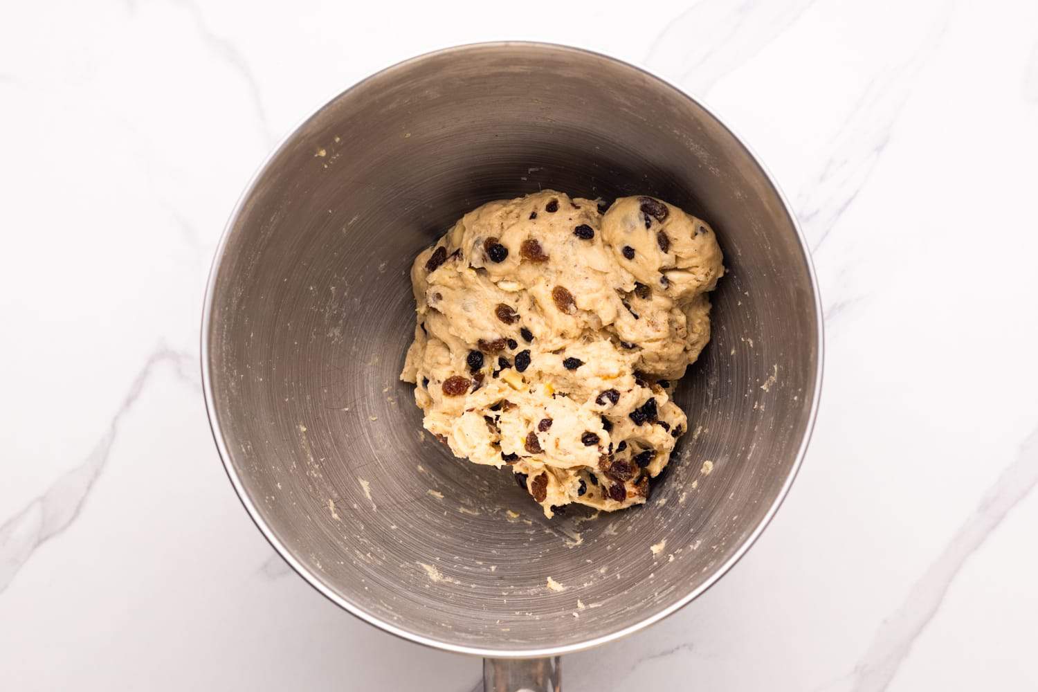 stollen dough in a stand mixer bowl with dried fruits and nuts kneaded in. 