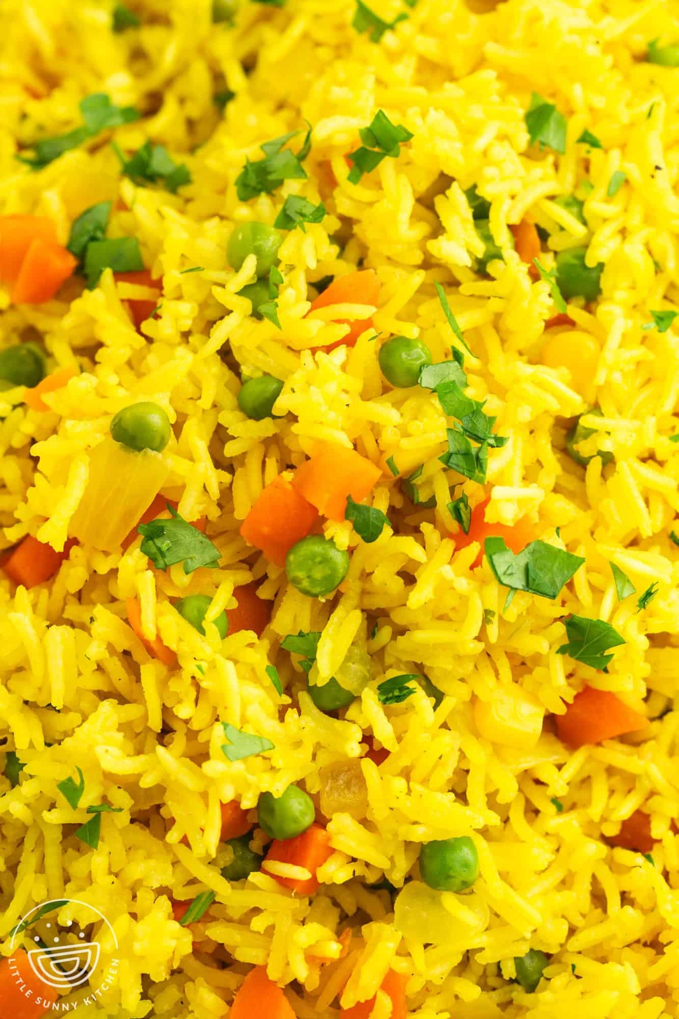 closeup of vegetable rice, colored yellow with turmeric, and including onions and mixed veggies.