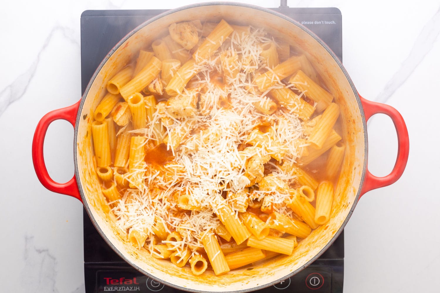 shredded cheese added to one pot chicken parm pasta in a dutch oven. 