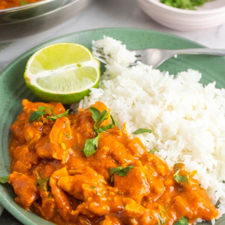 a green plate of coconut chicken curry with rice.