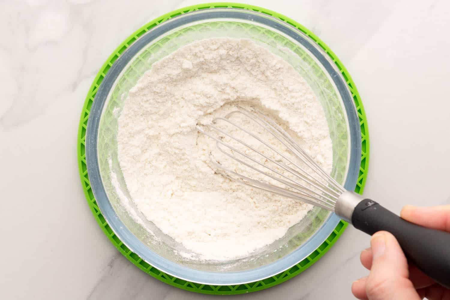 dry ingredients for pancake batter in a bowl with a whisk.