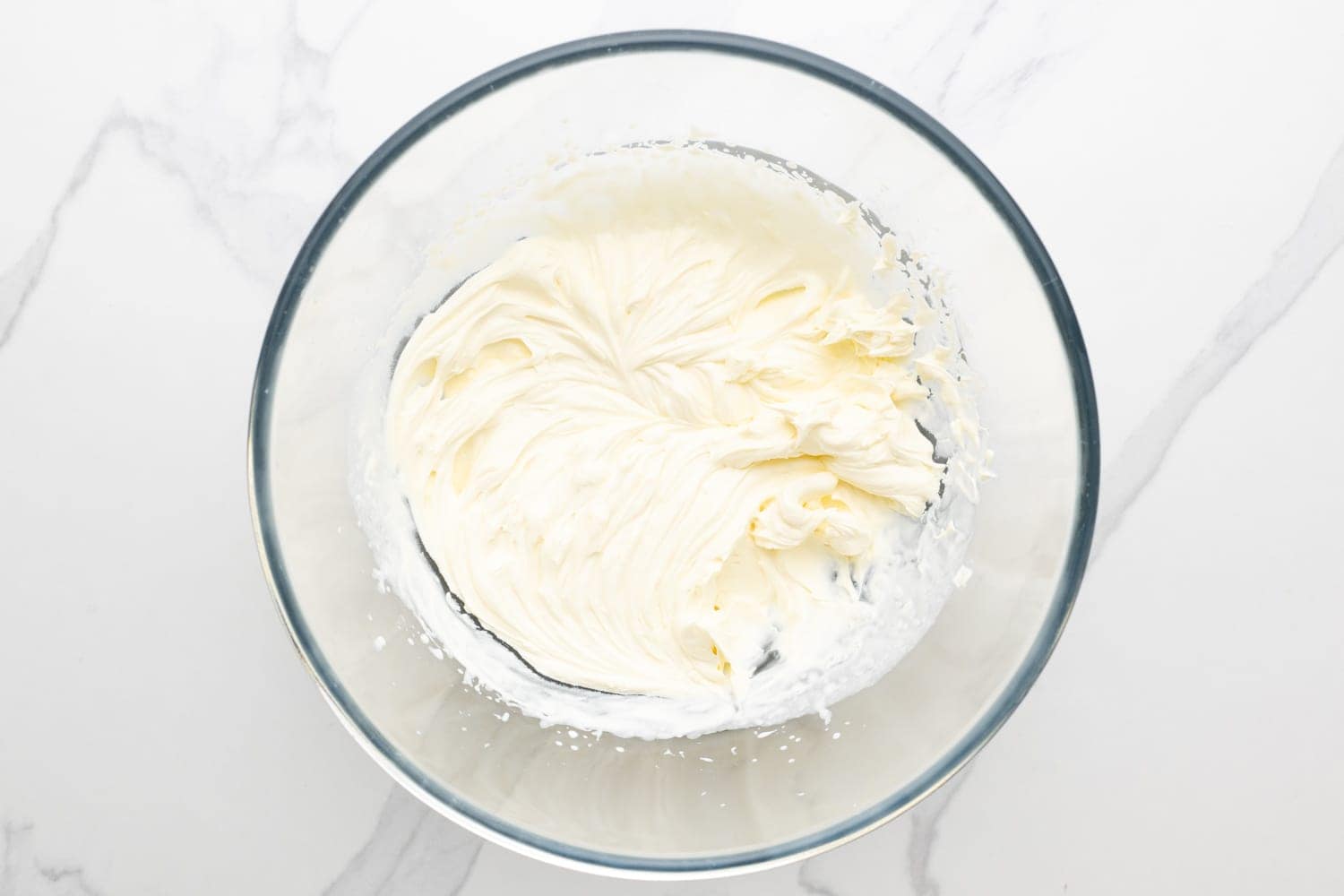 a glass mixing bowl of whipped cream.
