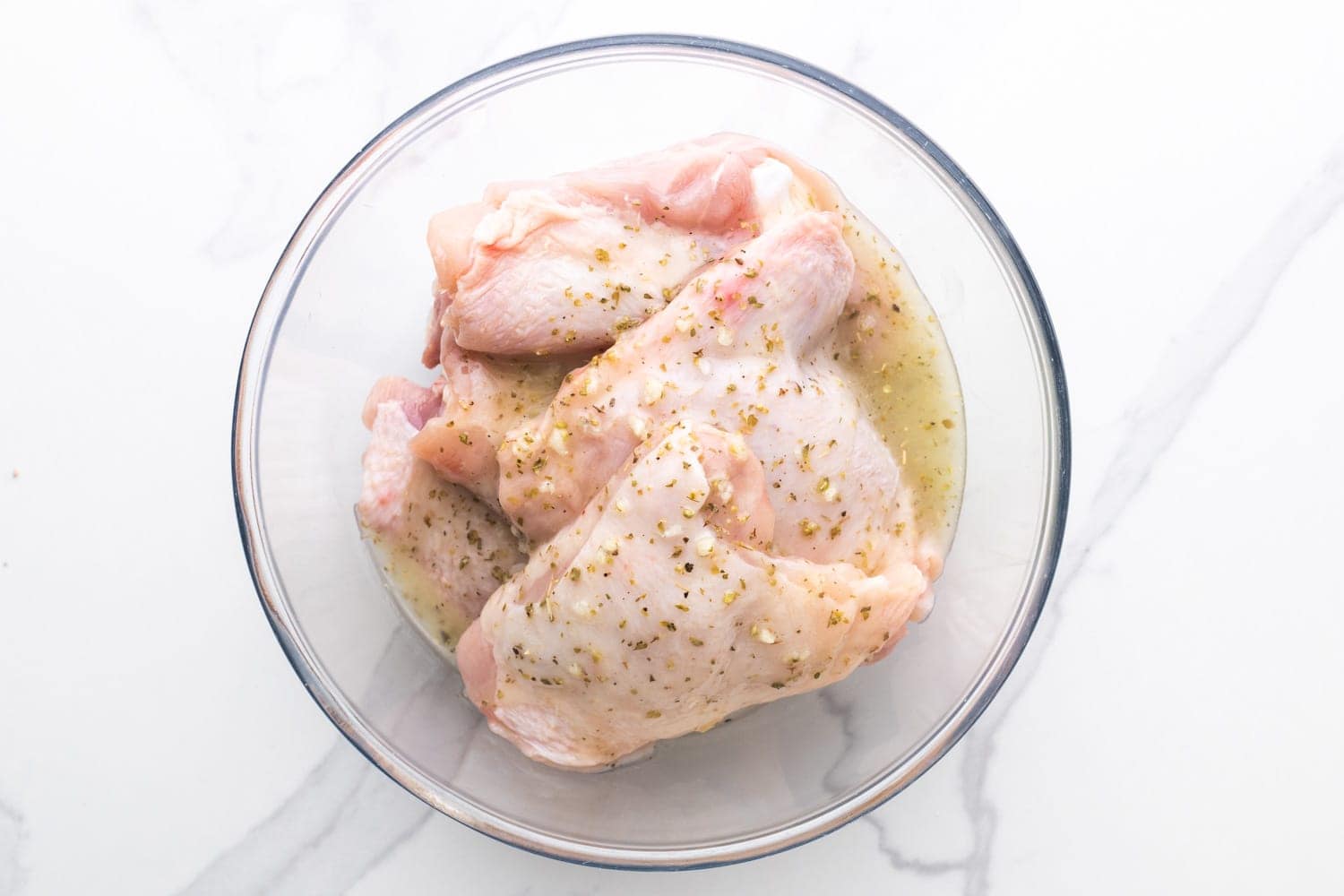 raw chicken thighs marinating in greek dressing. 