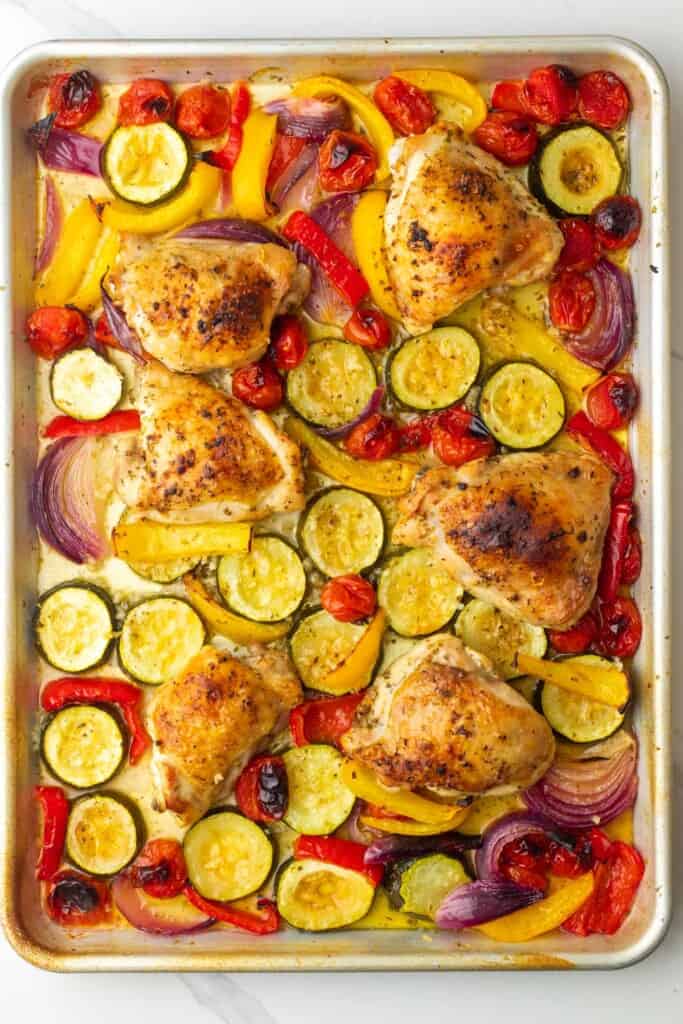 roasted vegetables and chicken thighs on a sheet pan. 