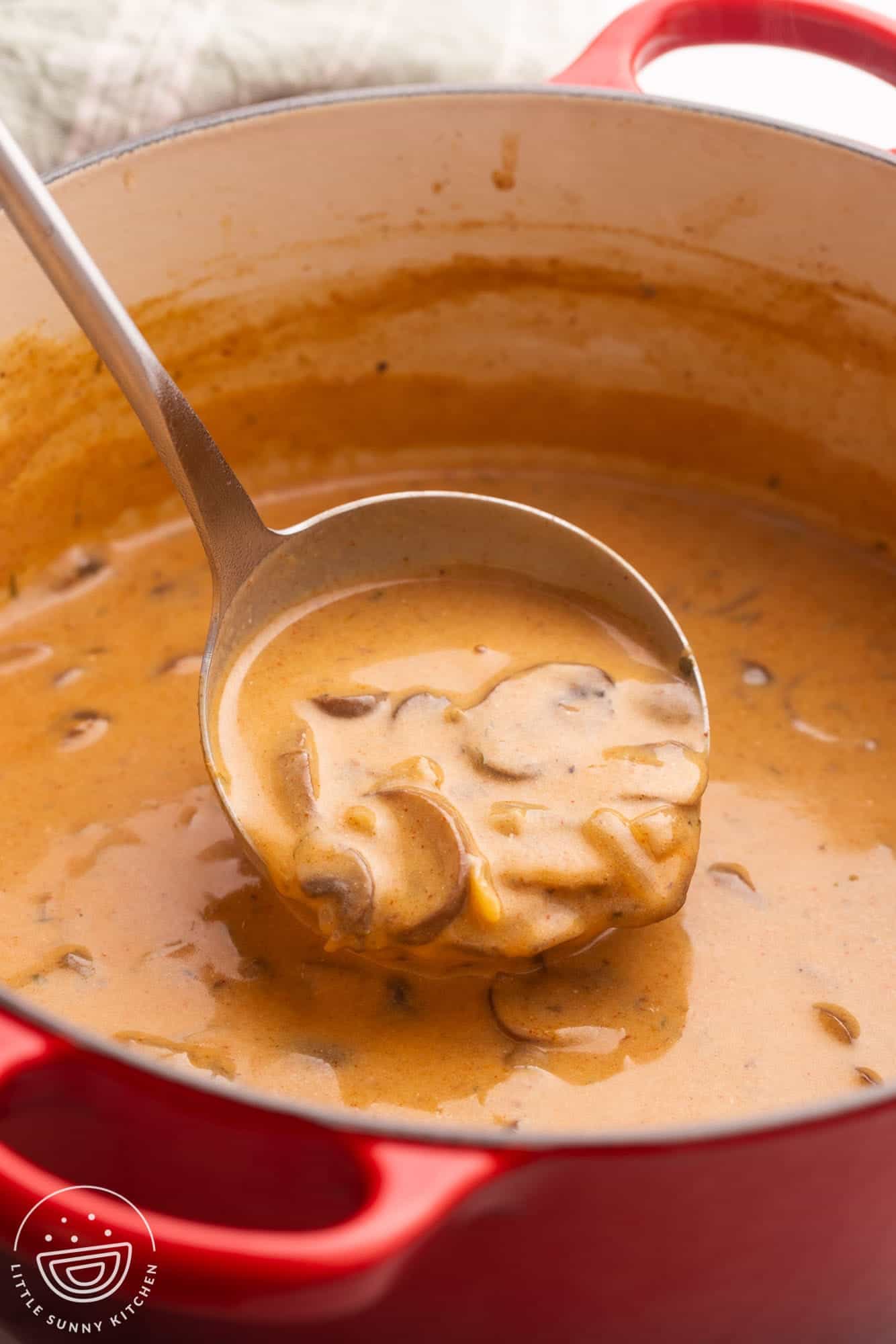 creamy hungarian mushroom soup in a dutch oven, served with a ladle.