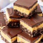 A stack of layered nanaimo bars on a white and black speckled plate.