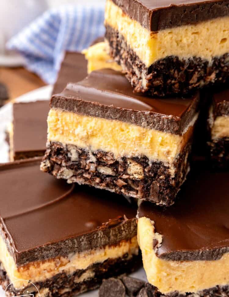 a stack of layered nanaimo bars with chocolate graham crust, custard filling, and chocolate topping.