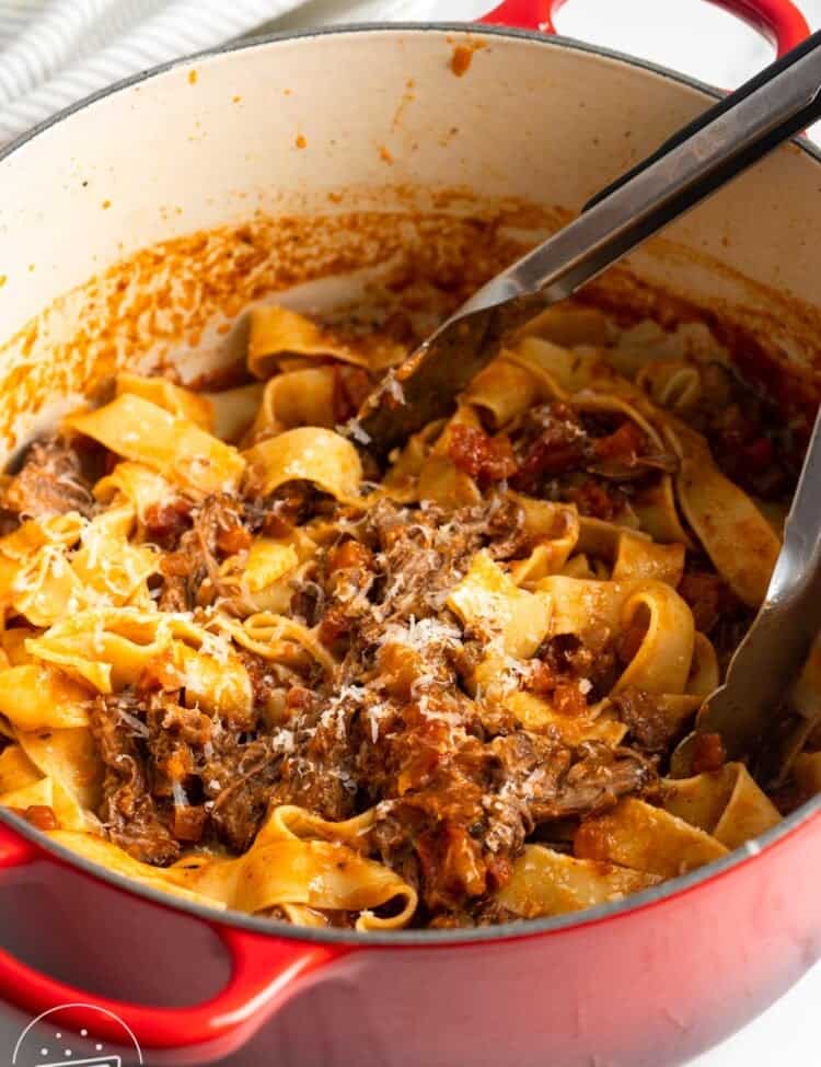 a dutch oven filled with pappardelle pasta and short rib ragu