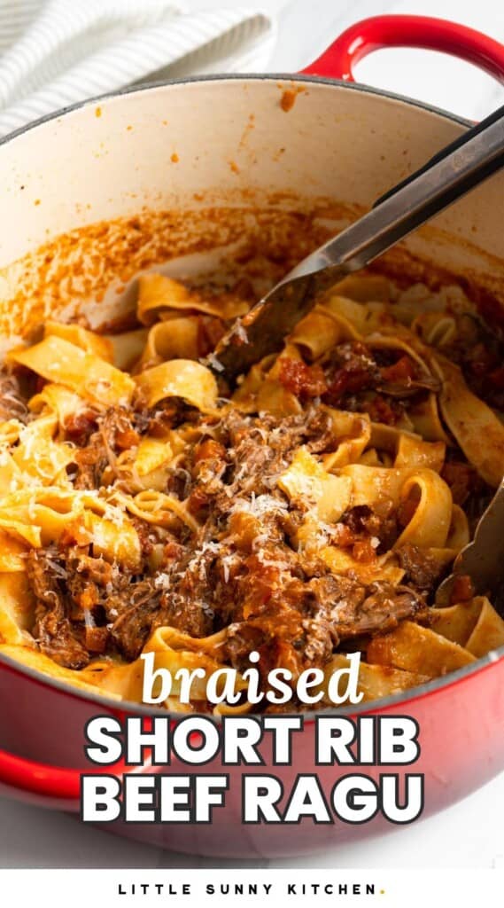 a red dutch oven holding pasta with beef ragu. Text overlay says "braised short rib beef ragu"