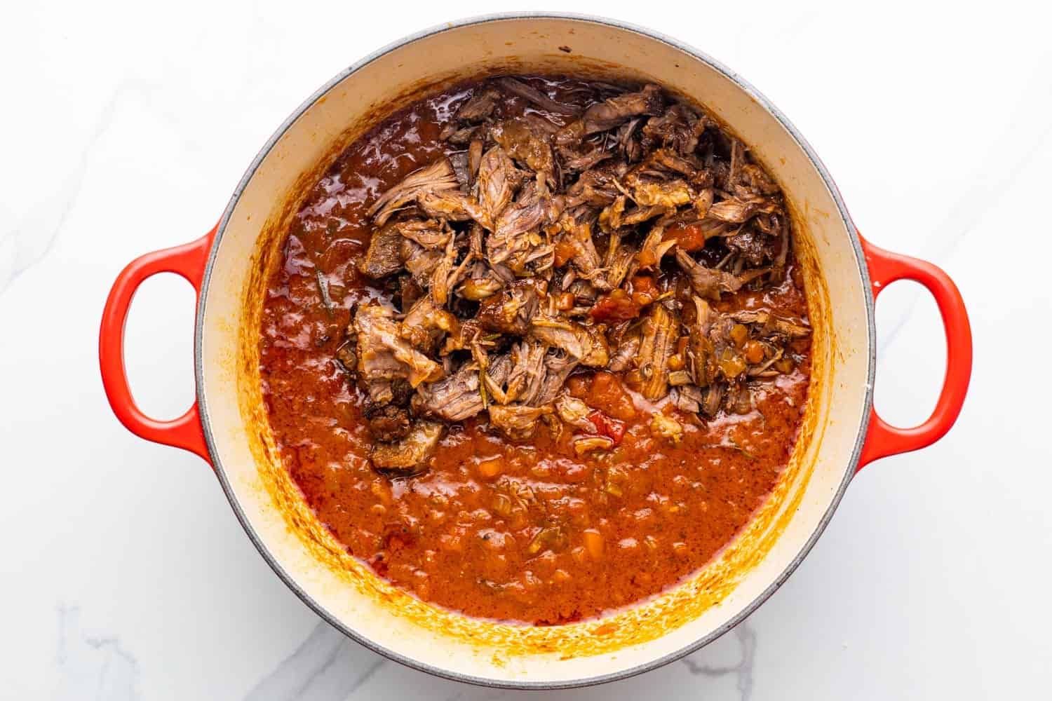 shredded beef added to a pot of homemade ragu. 