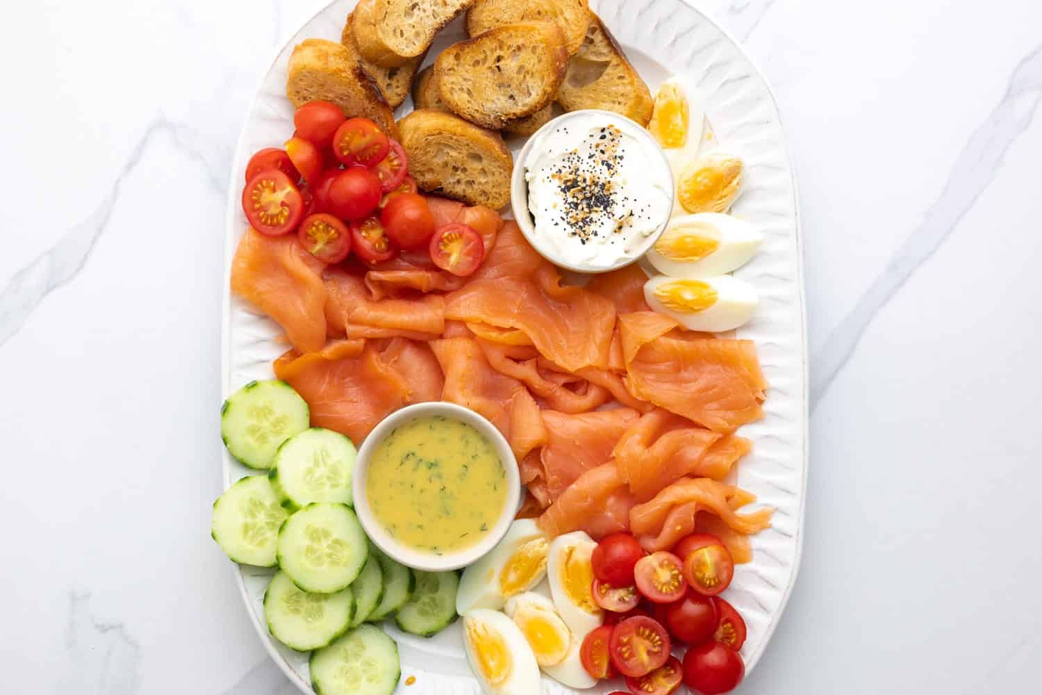 Smoked Salmon Platter with fresh vegetables, cream cheese, dill sauce, hard boiled eggs, and crostini.