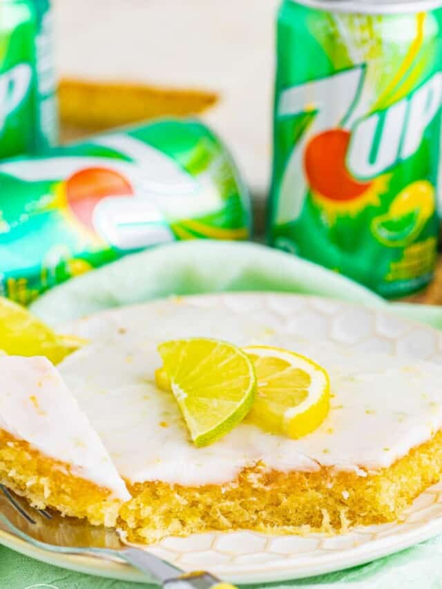 a slice of 7 up sheet cake on a plate. a fork is eating a bite. in the background are cans of pop.
