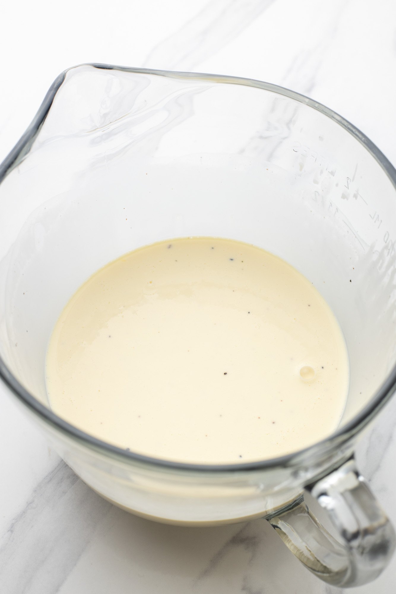 Eggs and cream mixed together in a glass measuring cup for quiche filling.
