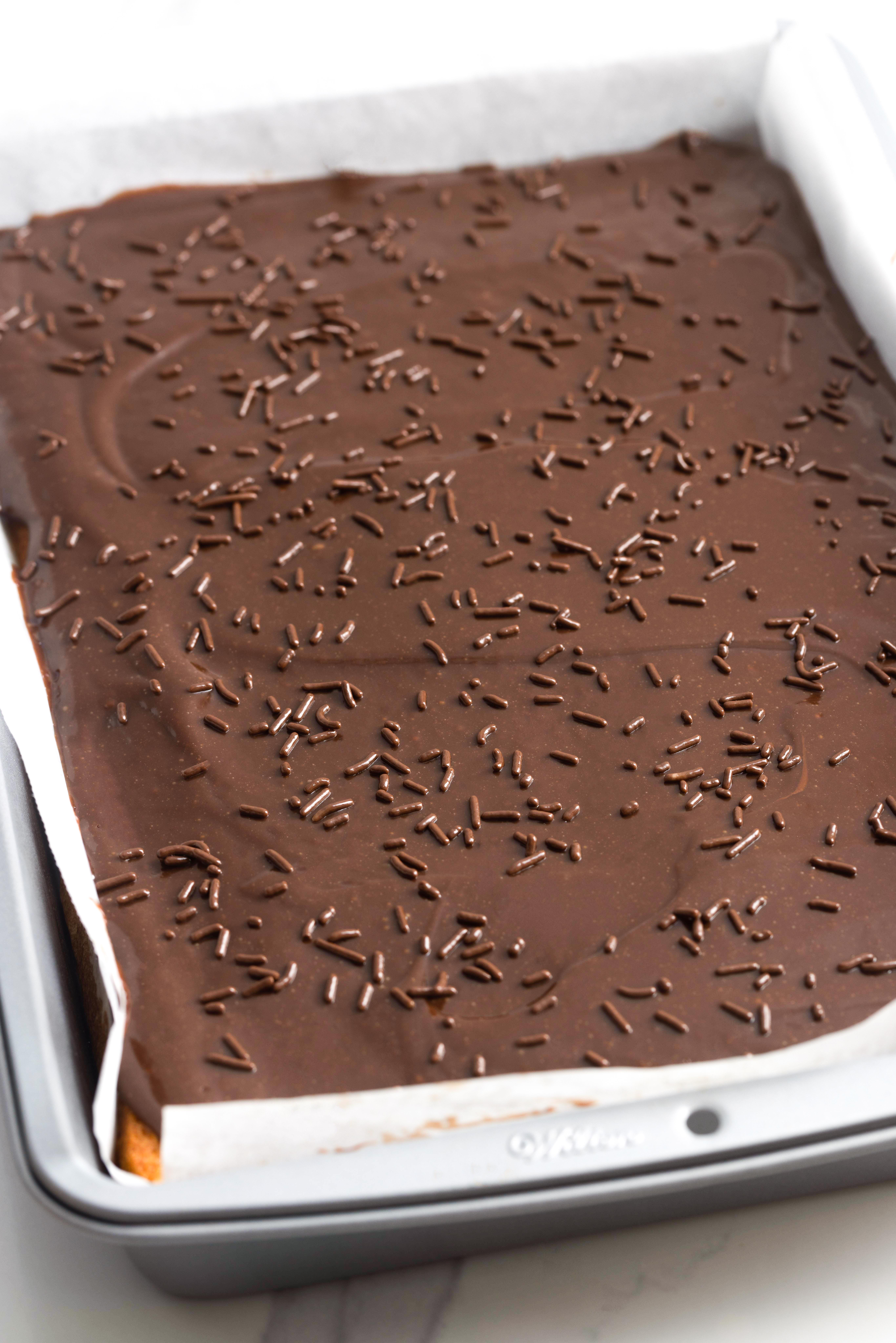 Brazilian carrot cake topped with chocolate frosting and chocolate sprinkles in a 9x13 cake pan.