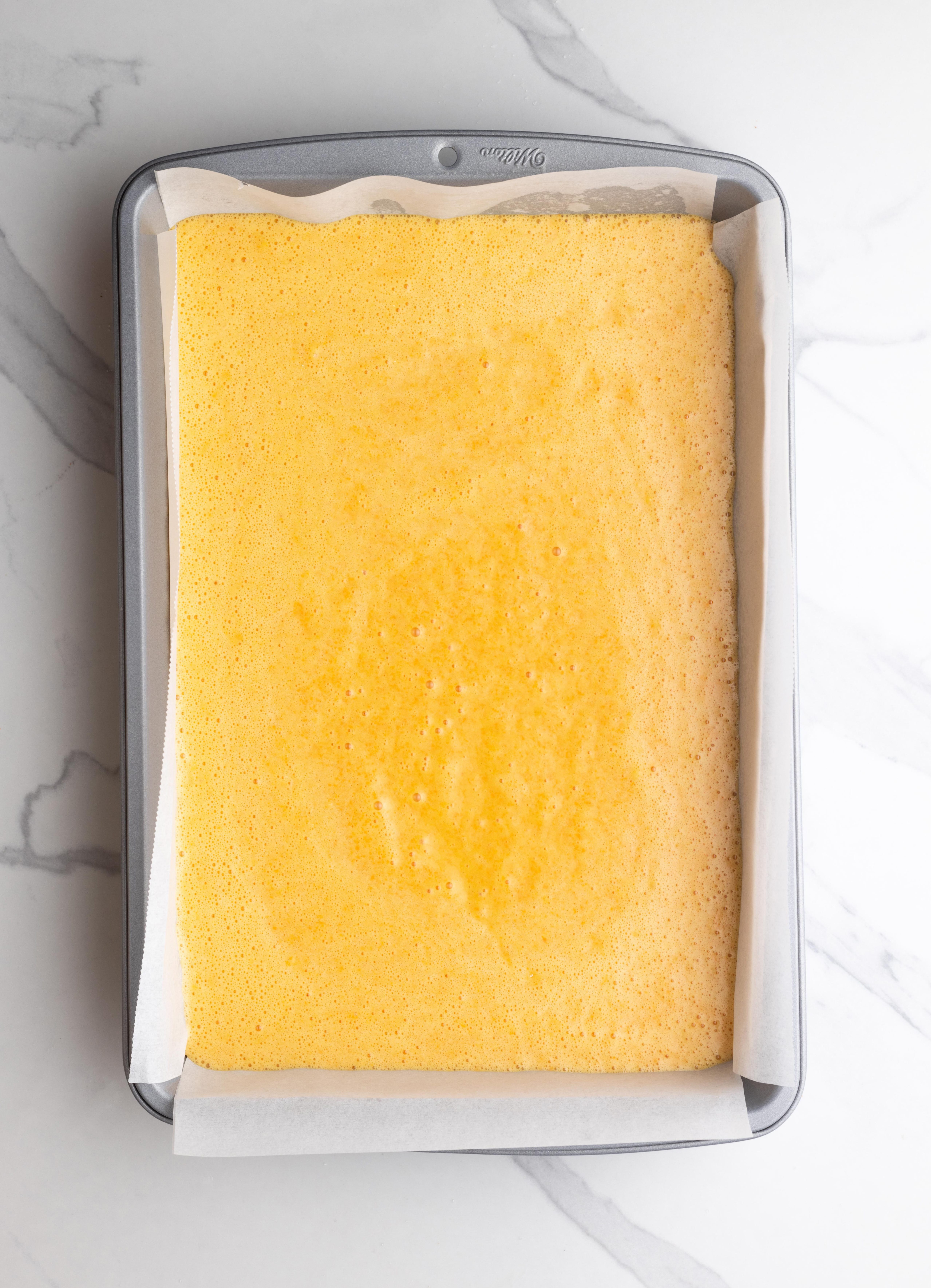 a rectangular cake pan lined with parchment paper and filled with Brazilian carrot cake batter.