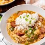 a plate of sausage and chicken gumbo with rice on a marble counter.