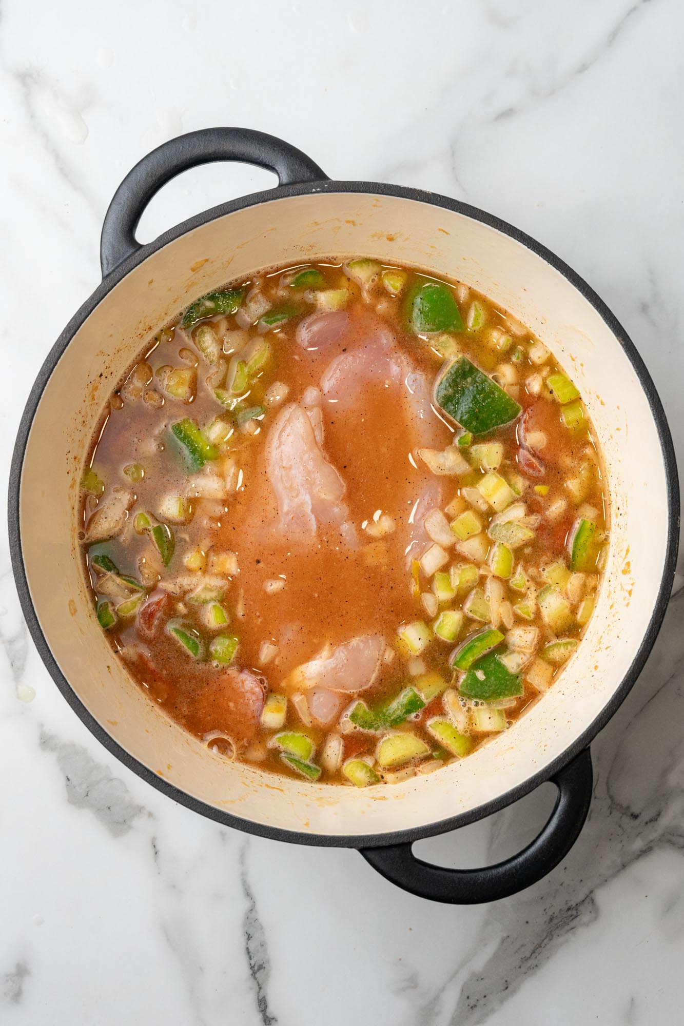 raw chicken breasts added to gumbo in a dutch oven.