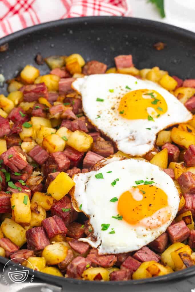 a skillet of homemade corned beef hash topped with two fried eggs.