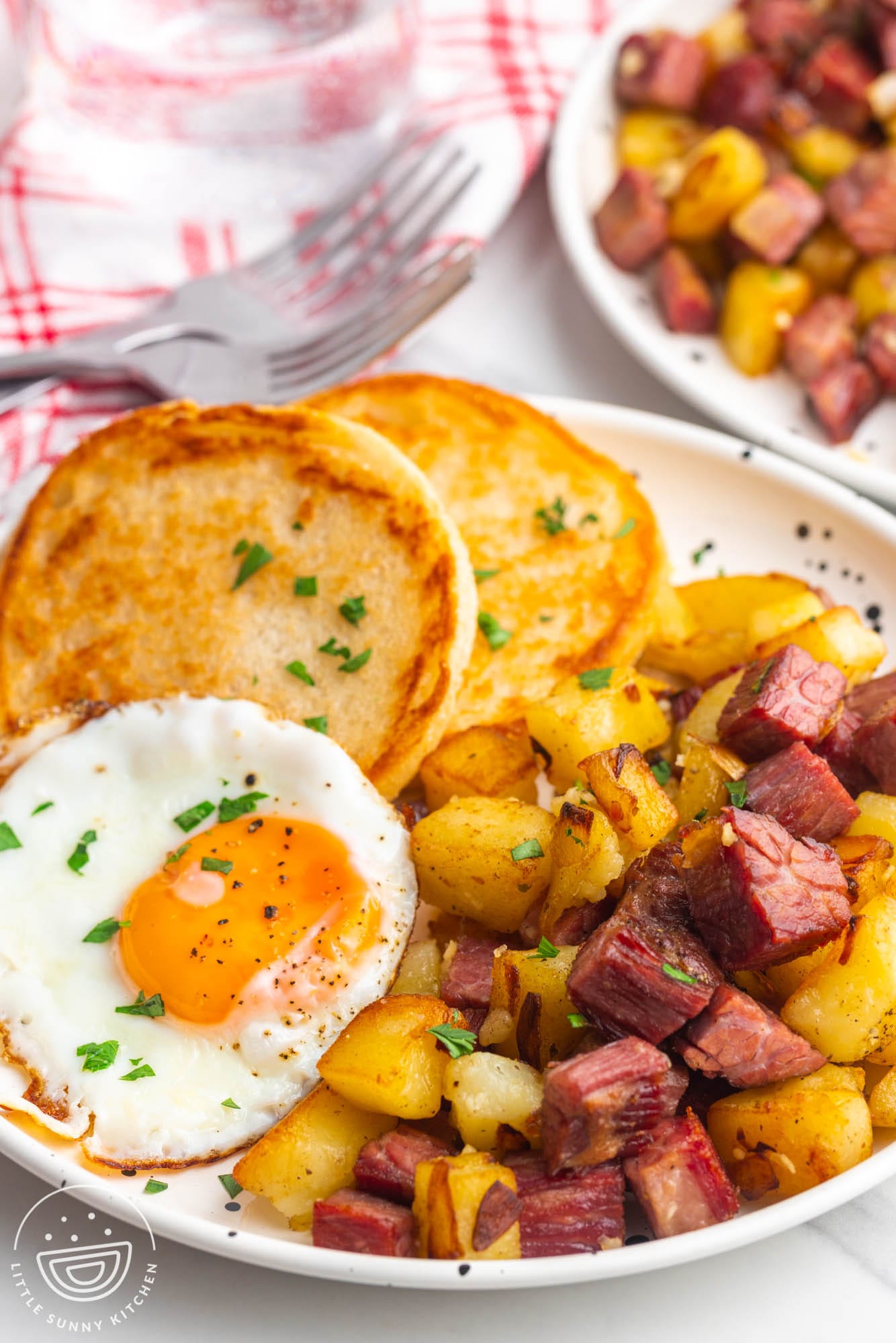 A plate of corned beef hash with toasted biscuits and fried eggs.