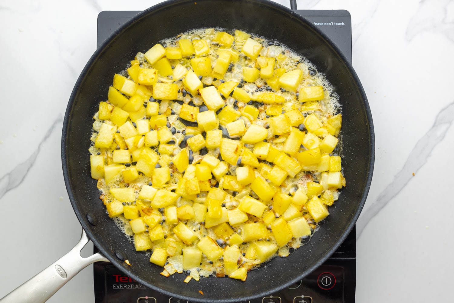 cooked diced potatoes and onions in a skillet over an electric burner.
